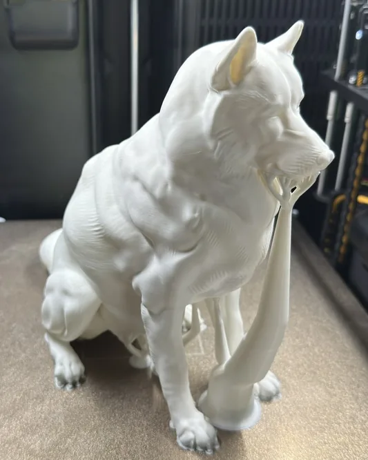 Finished white sculpture of a seated husky on the printer bed, with the supports still attached.